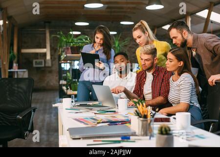 Agency coworkers discussing new project on laptop, working in modern office, free space Stock Photo