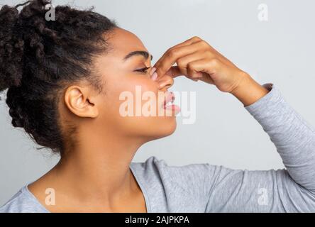 Side view of african young woman touching her nose, suffering from allergic rhinitis Stock Photo