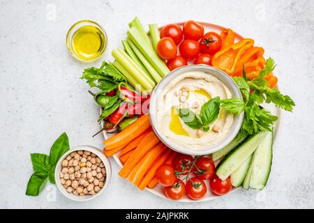 Hummus platter with assorted snacks. Hummus in bowl and vegetables sticks. Plate with Middle Eastern. Party, finger food. Top view. Vegan, hummus dip Stock Photo