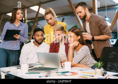 Freelance web designers brainstorming together, working on laptop in office Stock Photo