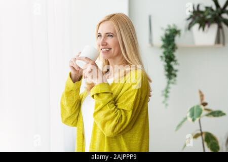 Perfect morning. Woman drinking coffee near window and daydreaming, copy space Stock Photo
