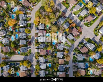 Aerial top down view of residential neighbourhood showing trees changing colour during fall season in Montreal, Quebec, Canada.