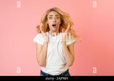 It's unbelievable! Woman shocked to see sales prices, girl looking at camera over pink background Stock Photo