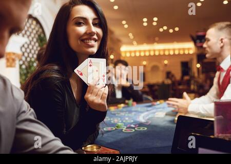 Girl with cards in her hands smiles at winning poker in a casino. Stock Photo