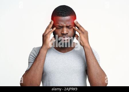 Young afro man having headache, touching his highlighted temples, migraine concept Stock Photo