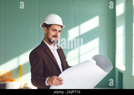 Foreman bearded man in a white helmet in a room at a construction site Stock Photo