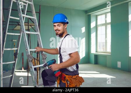 Builder contractor bearded man in helmet smiling while standing at a construction site. Stock Photo
