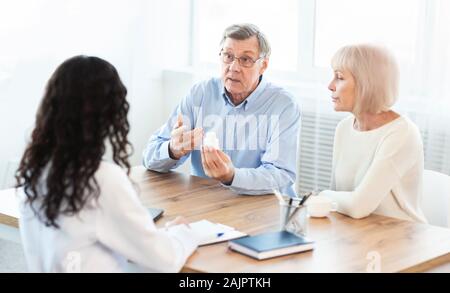 Treatment Concept. Senior man discussing prescription medicine with female caretaker at hospital, copyspace Stock Photo