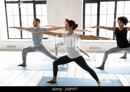 Diverse young people practicing yoga, doing Warrior two exercise Stock Photo