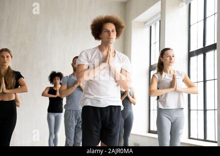 Diverse people holding hands in namaste, practicing yoga Stock Photo