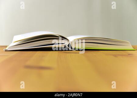 Open reading book, lying on the wooden table. Stock Photo