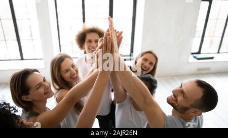 Close up diverse sporty people giving high five indoor Stock Photo