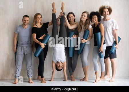 Indian woman doing Handstand, portrait smiling diverse people in studio Stock Photo