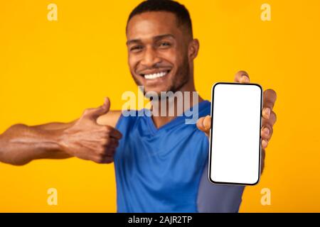 Sport App. Happy african man showing blank cellphone screen with thumb up, mock up, copyspace Stock Photo