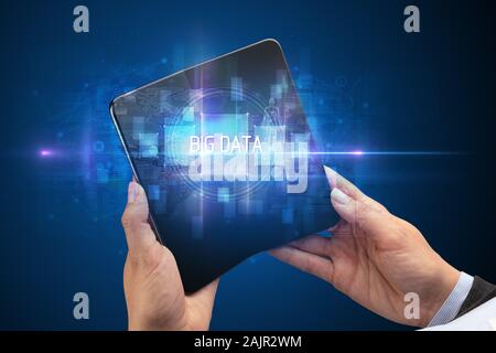 Businessman holding a foldable smartphone with BIG DATA inscription, new technology concept Stock Photo