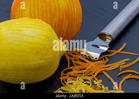 two citrus fruits on a slate plate with zest peeler and strips of peel Stock Photo