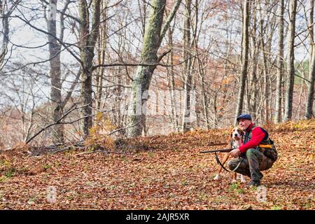 hunter with weapon and hunting dog chasing in the forest Stock Photo