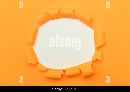 Orange paper with ripped hole in the middle background Stock Photo