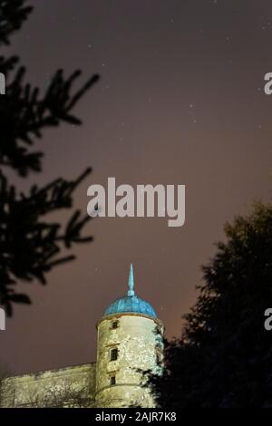 Janowiec castle under a star filled sky illuminated by light pollution from the village Stock Photo