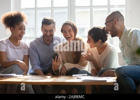 Overjoyed young people have fun using cellphone together Stock Photo