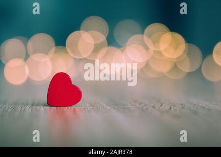 Stock photo of a small red wooden heart with a bluish background and unfocused light bulbs Stock Photo