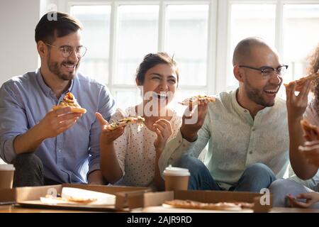 Happy multiethnic millennial friends have fun eating pizza together Stock Photo