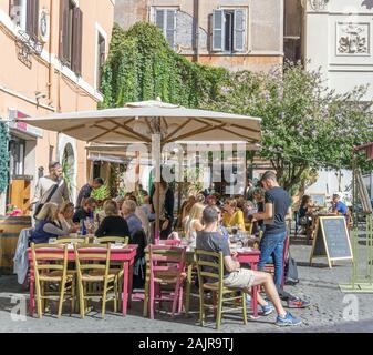 ROME, ITALY - OCTOBER 10, 2017: people are eating outdoors in a typical trattoria in Trastevere, historic district of Rome, Italy