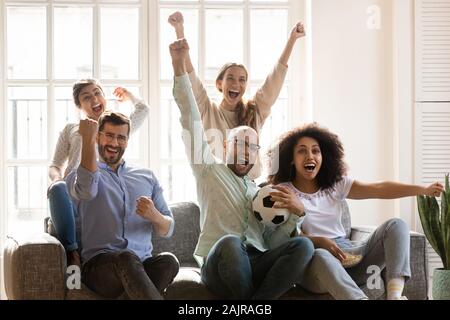 Overjoyed multiethnic friends watch football at home together Stock Photo