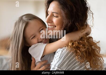 Closeup view beautiful young mother snuggle little cheerful daughter Stock Photo