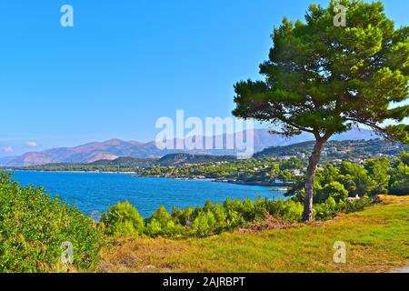 A stunning elevated view across a pretty bay near Lassi, looking towards Argostoli, with mountains in the background.  Tree in foreground. Stock Photo