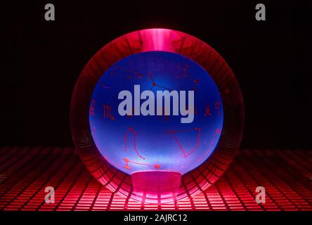 Glass ball photographed on a perforated plate with red light. Stock Photo