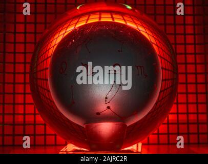 Glass ball photographed on a perforated plate with red light. Stock Photo