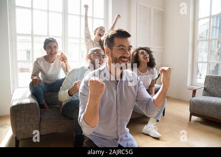 Overjoyed multiracial friends watch football at home online Stock Photo