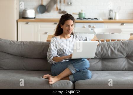 Female holding on lap notebook looking at screen writing email Stock Photo