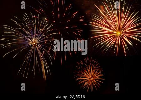 multiple bursts of colorful fireworks against black sky at holiday celebration Stock Photo