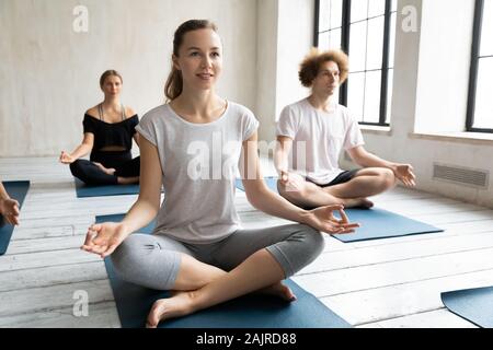 Young sporty people practicing yoga, doing Sukhasana exercise Stock Photo