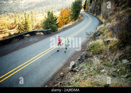 Two runners in their mid 20s running along scenic road in Rowena Stock Photo