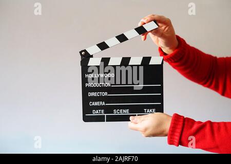 Woman dressed in red holding a black movie clapboard. Concept of action and cinema. Stock Photo
