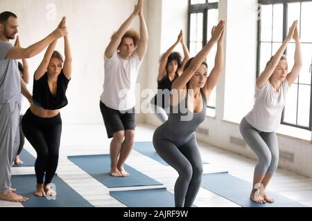 Diverse people doing Chair exercise, practicing yoga at group lesson Stock Photo