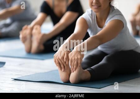 Indian woman doing Seated forward bend close up, practicing yoga Stock Photo