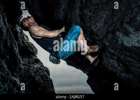 Man bouldering on coastal rocks Stock Photo