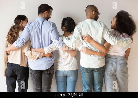 Back view of happy international young people stand hugging Stock Photo