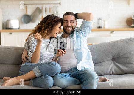 Cheerful married couple having fun using online amusing apps Stock Photo