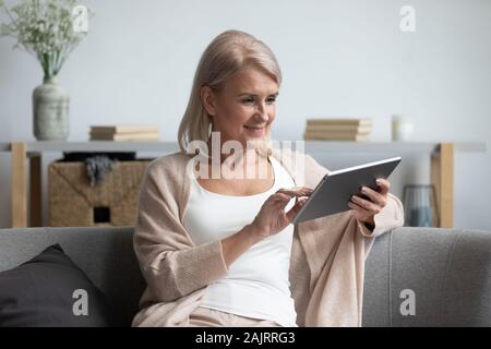 Elderly woman relax at home using electronic tablet Stock Photo