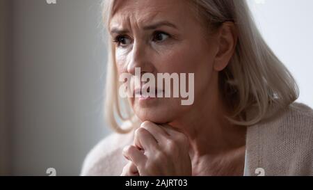 Close up of sad senior woman look in distance thinking Stock Photo