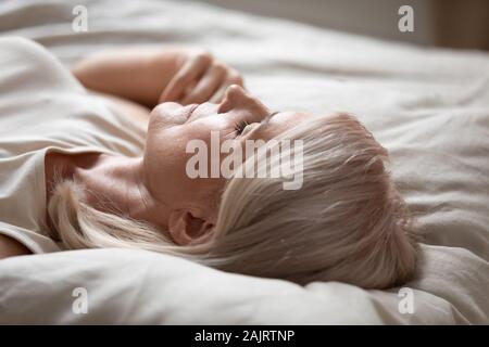 Tired mature woman relax sleeping in comfy bed Stock Photo