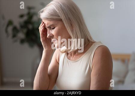 Unhealthy senior woman suffering from migraine at home Stock Photo