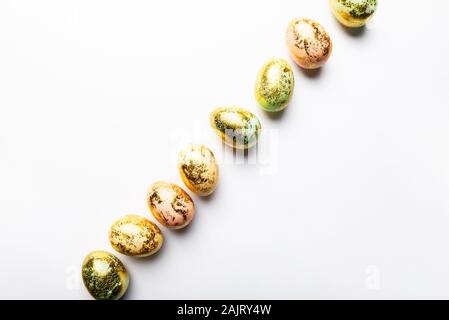 Natural Golden Speckled Easter Eggs of pastel colors on white background. Happy Easter card concept, minimalistic design, copy space Stock Photo