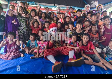 Kids pose with the clowns during the event. The Community “Aku Badut Indonesia” (I am Indonesian Clown) entertains a number of children affected by the floods that following torrential rains since the past 5 days. The activity is aimed at trauma healing and a form of caring for Jakarta flood victims, especially children. Stock Photo