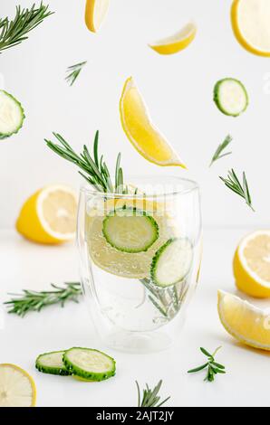 Food levitation concept. Detox water with lemon, cucumber and rosemary in a glass on white background. Weight loss and healthy lifestyle. Stock Photo